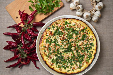 Kish of chicken on the table. Decorated with parsley, near the red pepper, garlic and greens on the...
