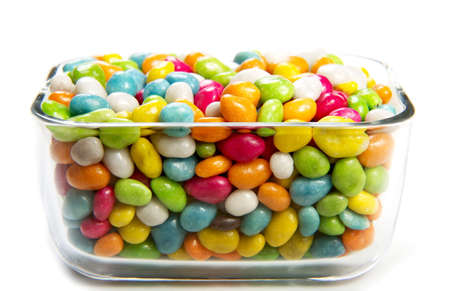 Colorful candies in glass vase on white background
