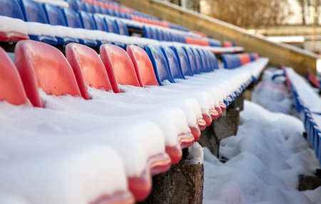 Partially snow covered red and blue seats in the stadium.の写真素材