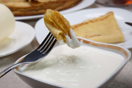 Piece of pancake in sour cream on a fork. Closeup.の写真素材