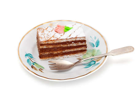 A piece of sponge cake with fork on plate, isolated on white background