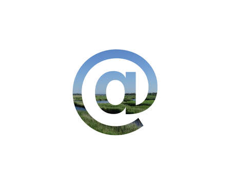 at sign, mail sign of the alphabet made with landscape with grass, stream and a blue skyの写真素材