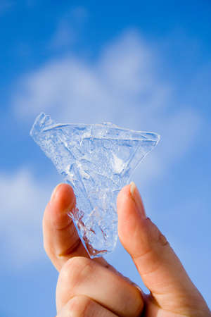 bit of ice in hand on blurred sky backgroundの写真素材