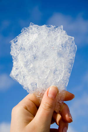 bit of ice in hand on blurred sky backgroundの写真素材