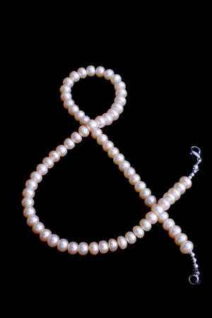 pink pearl's bead as a & sign isolated on blackの写真素材