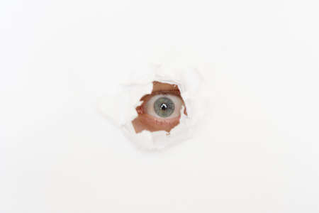 eye of eavesdropper in the hole of white paperの写真素材