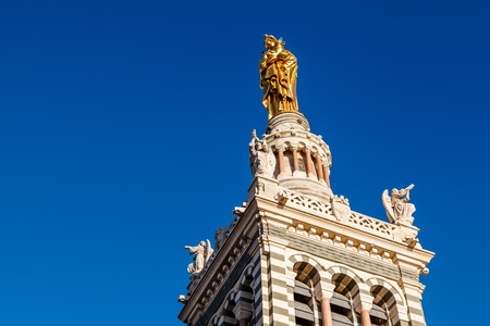 Golden Statue of the Madonna Holding the little Jesus on the top of Notre-Dame de la Garde in Marseilles, Franceの写真素材