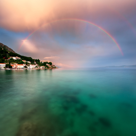 Rainbow over Rocky Beach and Small Village after the Rain Dalmatia Croatiaの写真素材