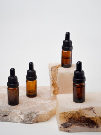 Essential oil in a brown glass bottle on a white background.a white skincare bottle with a plant flower theme on a white background and a blue towelの写真素材