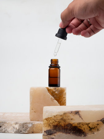 Essential oil in a bottle with pipette on natural stone background, essential oil bottle with blue...