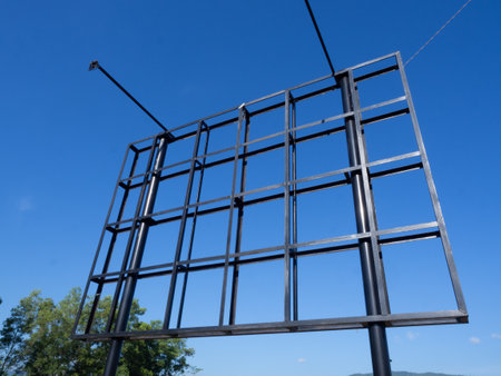 Basketball hoop against the blue sky, close-up of photodetail outdoor billboard in black checkered pattern with lights on the right and left, against a bright blue sky backgroundの写真素材