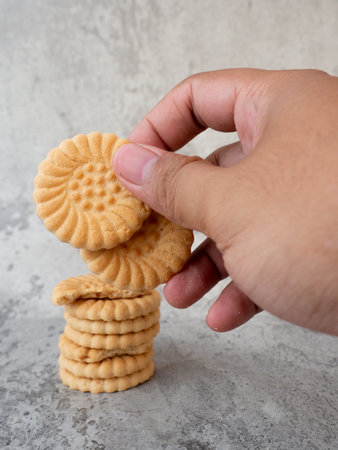 Hand holding a stack of cracker cookies on a gray background.の写真素材