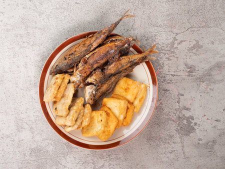 fried fish with potatoes in a plate on a gray background, top viewの写真素材