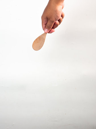 Hand holding a wooden spoon on white background, shallow depth of fieldの写真素材