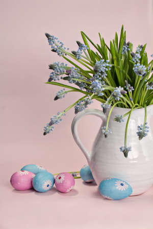 Blue hyacinths in a white vase with colored eggs and a pink backgroundの写真素材