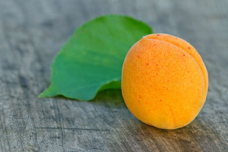 Apricot and a green leaf on a wooden table backgroundの写真素材
