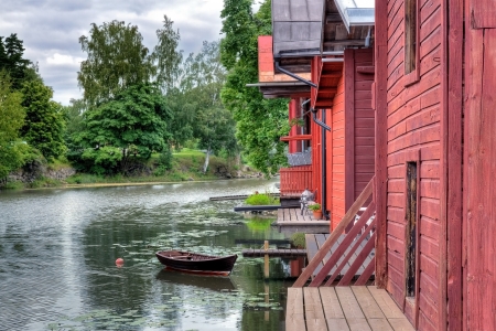 Red wooden buildings and a rowing boat by a river in Porvoo Finlandの写真素材