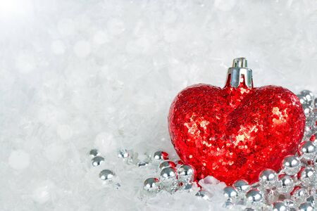 Glittering read heart with silver decorative beads with snowflakes and bokeh backgroundの写真素材