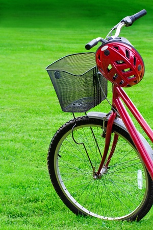 Close-up of womenÕs red mountain bike and a helmet in green grass summer backgroundの写真素材