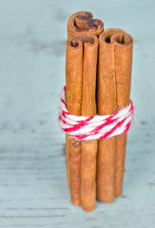 Bunch of cinnamon sticks on light blue wooden shabby chic backgroundの写真素材