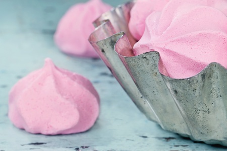 Pink meringue in a rustic cupcake bowl with shabby chic blue wooden backgroundの写真素材
