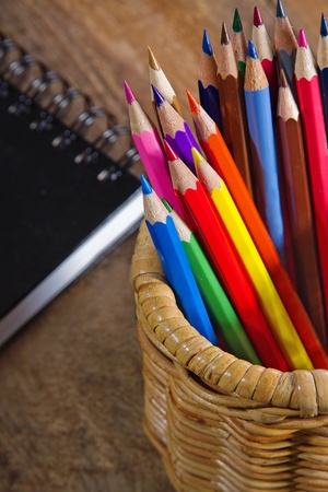 Closeup of colored pencils and a black notebook on wooden rustic backgroundの写真素材