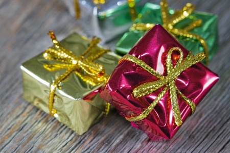 Small Christmas presents wrapped in shiny paper on wooden rustic background