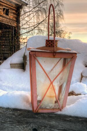 Rustic lantern in snowy winter evening in front of an old wooden barnの写真素材