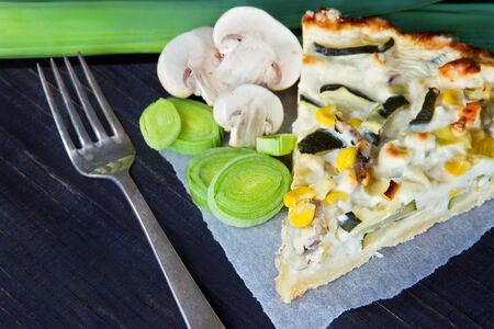 Vegetable quiche on dark wooden background with leek and mushroomの写真素材