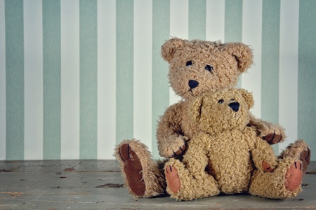 Vintage setting of two teddy bears hugging, striped green backgroundの写真素材