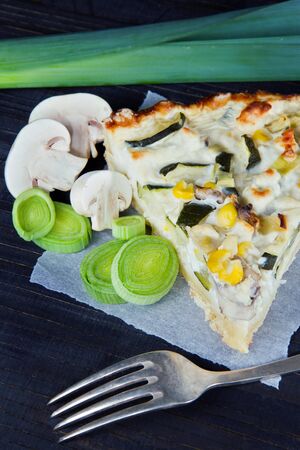 Vegetable quiche on dark wooden background with leek and mushroomの写真素材