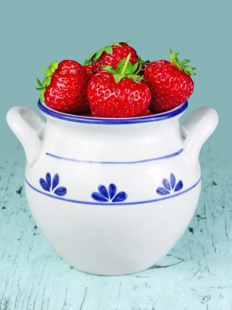 Fresh strawberries in a white bowl on light blue wooden rustic backgroundの写真素材