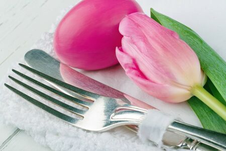 Closeup of pink easter dinner setting, with egg, rustic cutlery and tulipの写真素材