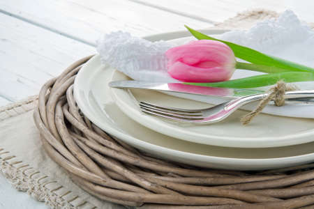 Pink tulip on rustic dinner setting on white wooden tableの写真素材
