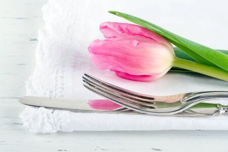Closeup of pink tulip at rustic dinner setting, on white wooden tableの写真素材