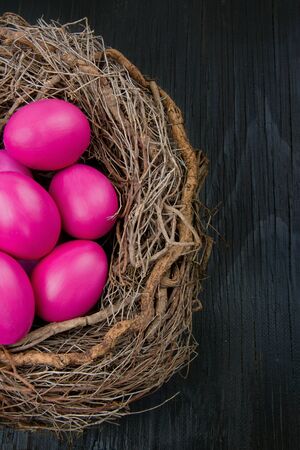 Pink easter eggs in a nest on dark wooden backgroundの写真素材