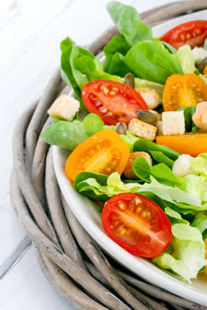 Salad with tomatos and croutons on a plate - fresh and healthy lunch on a rustic wooden tableの写真素材