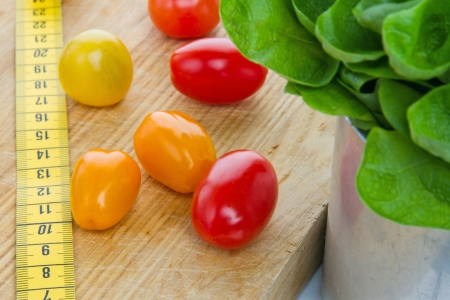 Salad, tomatos and measurement tape - diet and healthy eating; weight loss conceptの写真素材