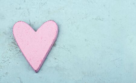 Single pink heart on light blue wooden table - shabby chic Valentine's day backgroundの写真素材