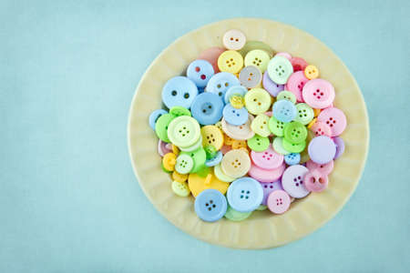 Light yellow plate full of pastel colored buttonsの写真素材