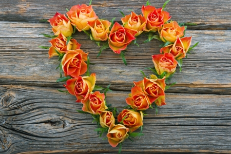 Orange roses in heart shape on wooden backgroundの写真素材