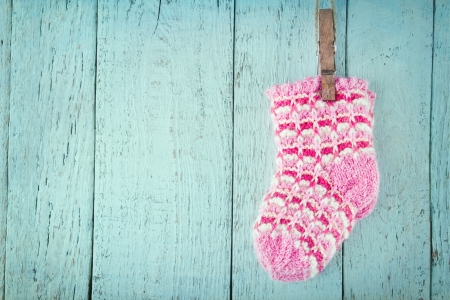 Pink baby socks on a blue wooden rustic background with copy spaceの写真素材