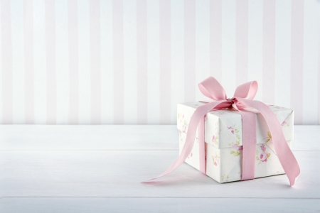 Floral pattern gift box tied with pink ribbon on white wooden background with copy spaceの写真素材