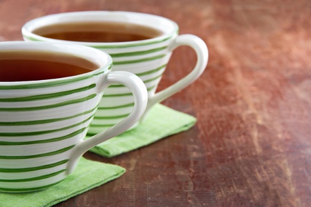 Two green striped cups of tea on wooden rustic backgroundの写真素材