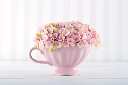 Pink hydrangea flowers in a shabby chic mug on vintage background with copy space