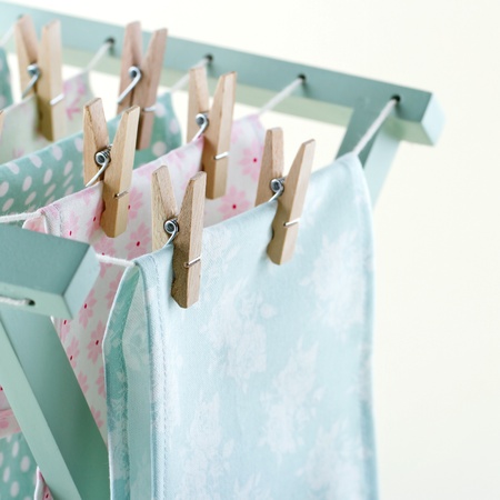 Closeup of pastel color laundry drying on vintage wooden drying rack with copy spaceの写真素材