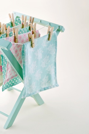 Closeup of pastel color laundry drying on vintage wooden drying rack with copy space