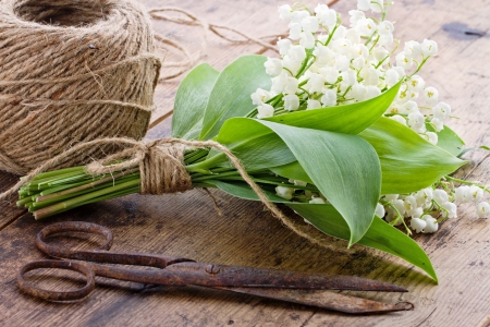 Bouquet of spring flowers lilys of the valley with old rusty antique scissors and ball of brown twineの写真素材