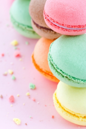 Two piles of colorful macaroons on pastel pink background with small crumbsの写真素材