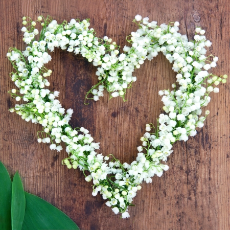 Heart shaped flower wreath of lilys of the valley on rustic wooden backgroundの写真素材